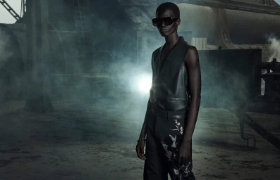 Mamuor Majeng wearing a sleeveless black leather vest and dark sunglasses in a smoky industrial setting for Zara Studio.