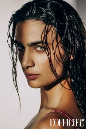 Close up portrait of a woman with wet dark hair and intense gaze against a light background for L'Officiel Baltics.