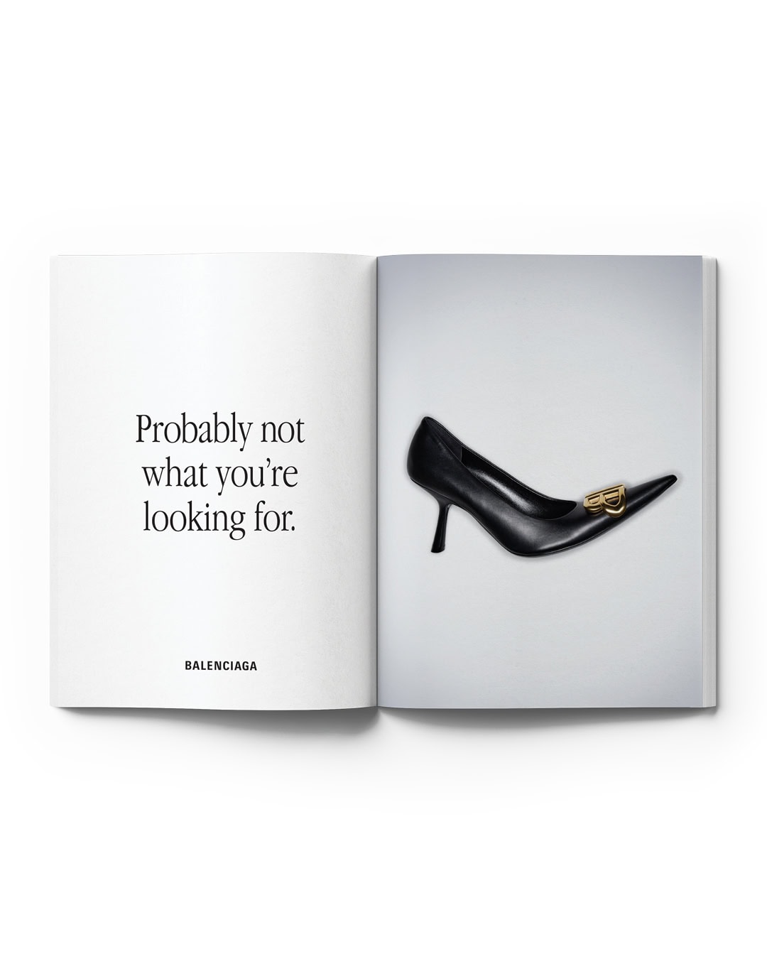 Black leather high-heel pump with gold logo on a magazine page, offset by contrasting text against a light gray backdrop.