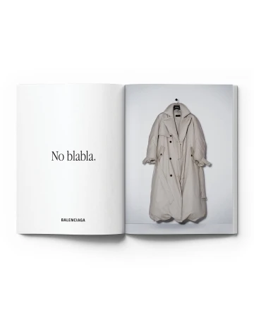 Fashion editorial featuring a spread in an open book with a beige trench coat on a hanger against a white wall, with 'No blabla' text.