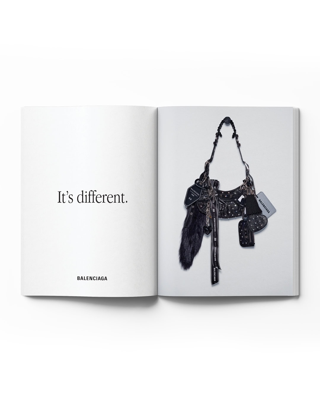 Open magazine featuring a Balenciaga purse and the text 'It's different.' The purse is detailed with black, white, and silver accents.