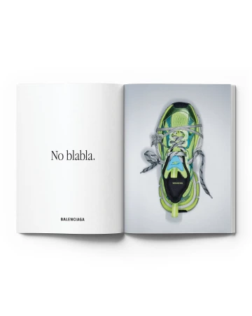 Open magazine featuring a lime green Balenciaga sneaker with blue accents, laces, and a thick sole, presented against a white background.
