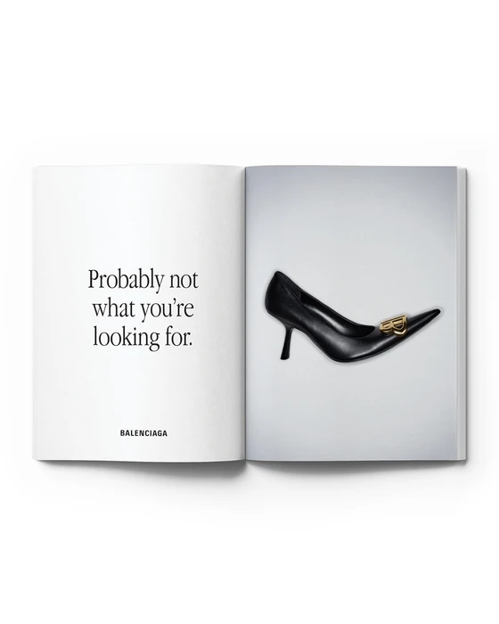 Open magazine spread displaying a black pointed-toe Balenciaga stiletto pump with gold hardware alongside minimalist text.