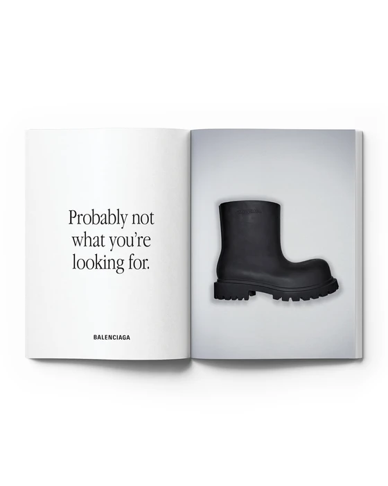Open book spread showing Balenciaga copy text opposite a chunky black matte rubber ankle boot on a light gradient background.