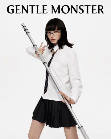 Stylish Asian woman in school uniform with glasses poses with a silver pole on a white background, featuring Gentle Monster logo.