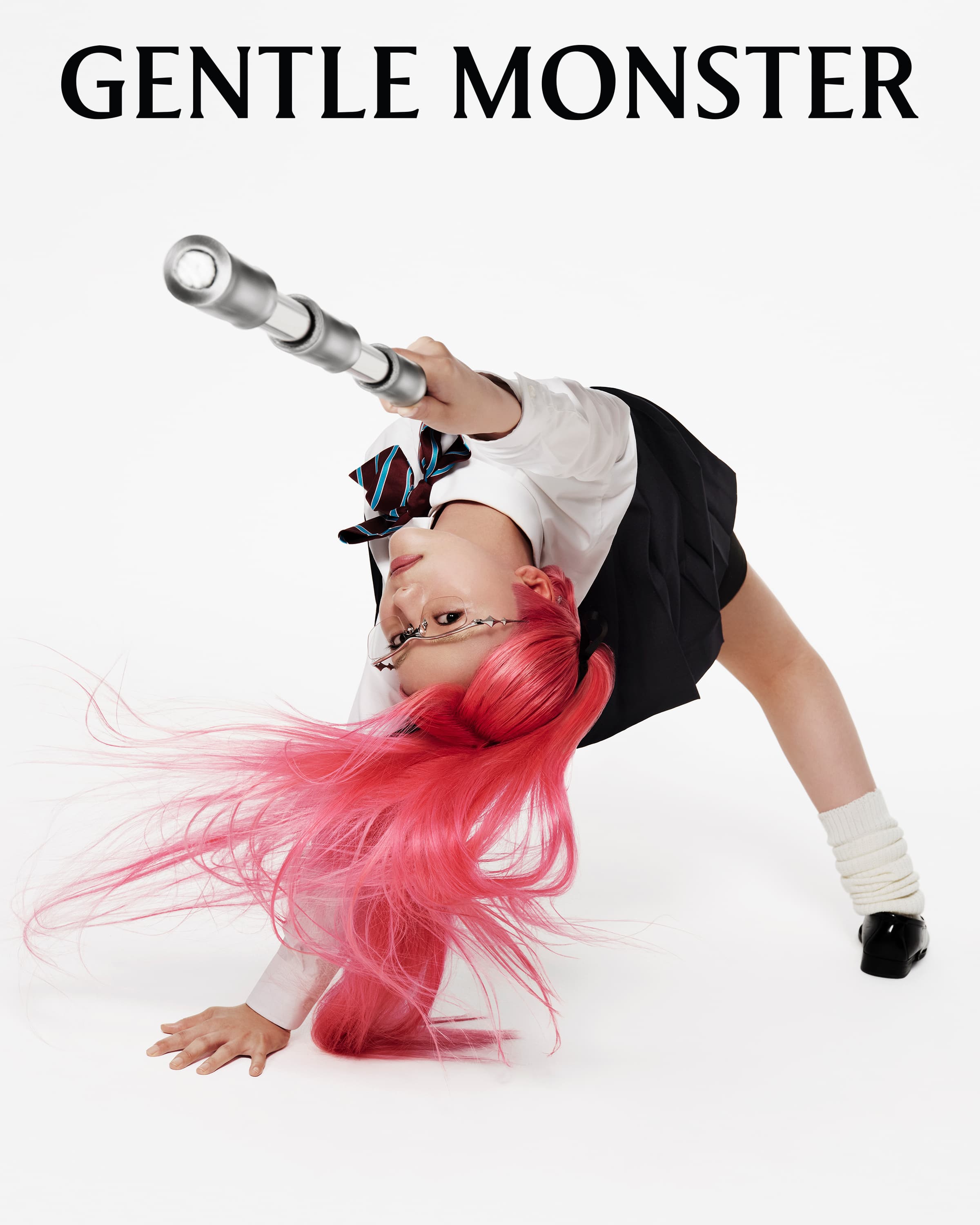 Person in school uniform bends over backwards holding cylindrical object with bright pink flowing hair against white background.