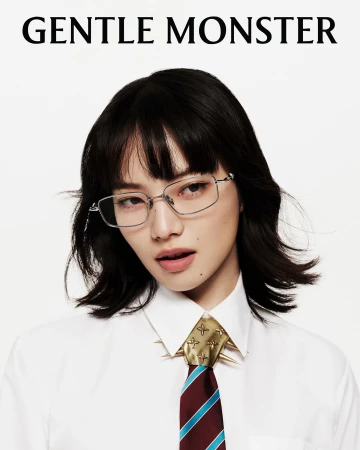 Asian woman in glasses, wearing a white shirt and patterned tie, poses against a white backdrop in a fashion-forward eyewear ad.