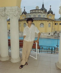 Model Yoesry Detre wearing an embroidered white shirt and beige trousers by a thermal pool in Budapest for COMMAS Resort 2024.