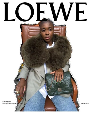 Woman in a trench coat and fur stole seated with a leather handbag, posing for a Loewe fashion brand ad.