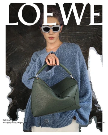 Taeyong wearing embellished sunglasses and a blue knit sweater holding a green leather Loewe handbag.