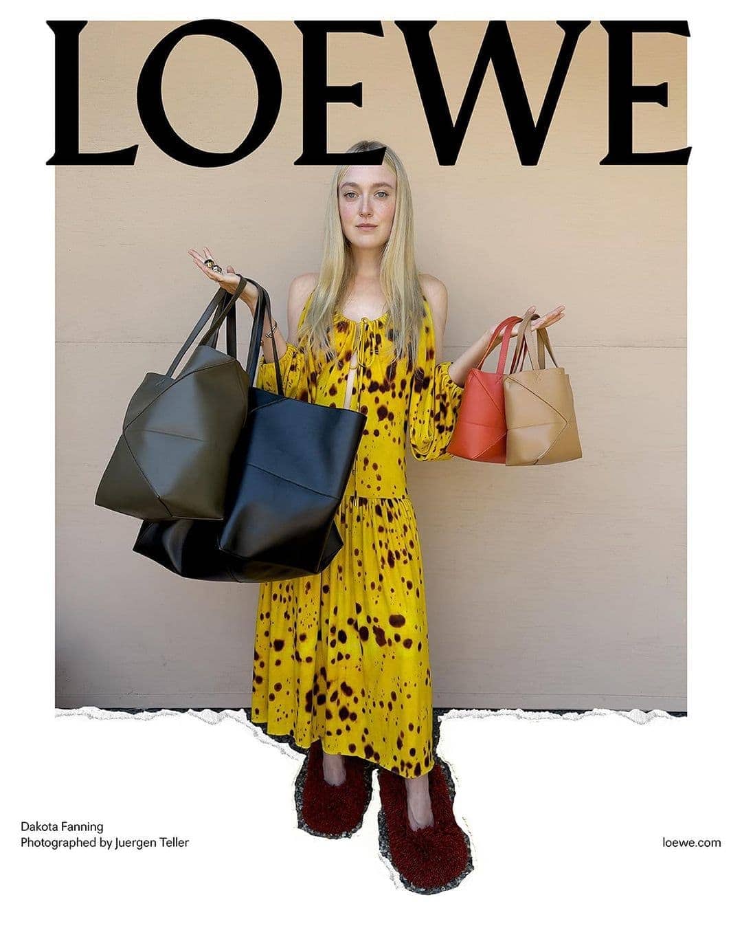 Dakota Fanning poses for a Loewe brand advertisement, holding multiple tote bags, wearing a yellow patterned dress and maroon slippers.