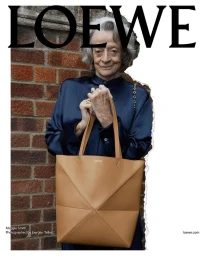 Dame Maggie Smith holding a large tan leather tote bag against a brick wall for the Loewe Pre-Spring 2024 ad campaign