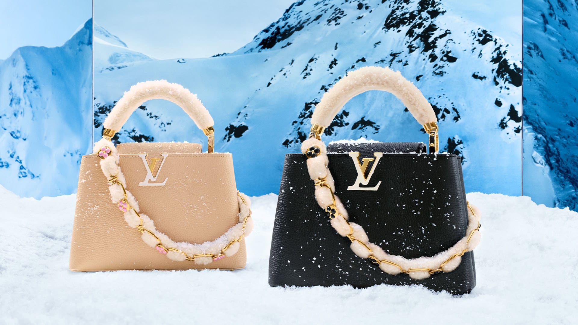 Two Louis Vuitton Capucines bags, one beige and one black, sit in snowy setting with snow-covered mountains visible in the background.