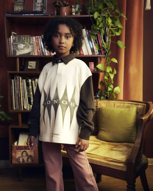 Young girl in a vintage-inspired outfit poses in front of a bookshelf with vinyl records, creating a nostalgic fashion portrait.