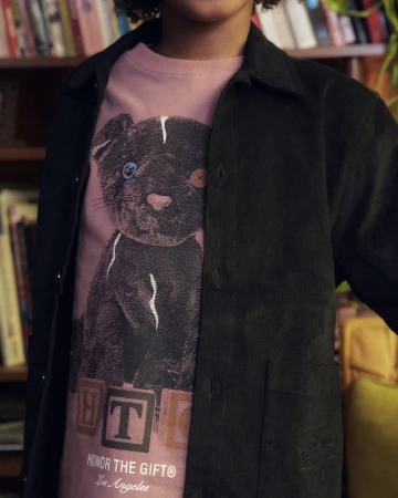 Person wearing a graphic t-shirt with a cartoon panther design, standing in front of a bookshelf with books and decor.