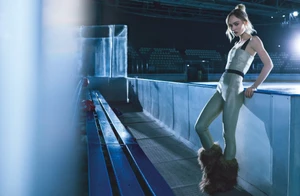 Lily-Rose Depp wearing a fitted pale jumpsuit and furry boots standing by a hockey rink for Chanel Coco Neige campaign.