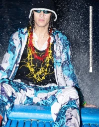 Model wearing blue patterned jacket and sunglasses amidst water splashes for Emocean 8 magazine