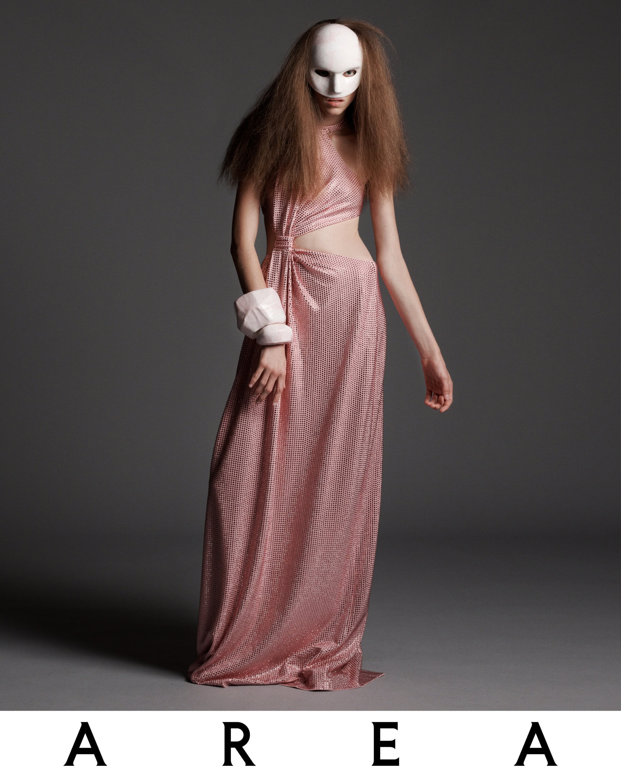A fashion shot features a slender model in a shimmering pink gown, wearing a mask, and posing against a gray backdrop with the brand 'AREA' displayed.