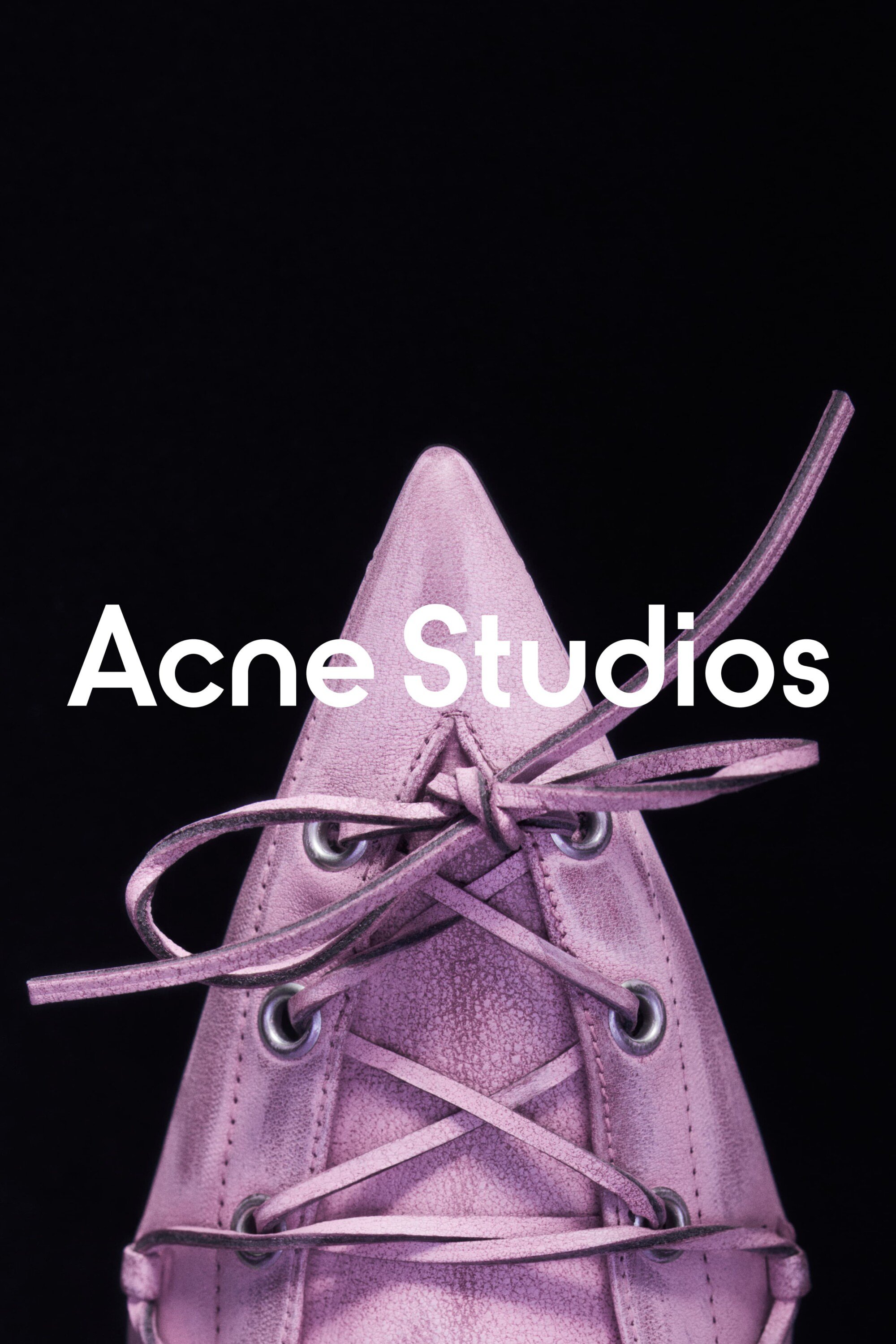 Close-up of a lavender-colored, lace-up, pointed-toe shoe against a solid black background. The brand logo, Acne Studios, is visible.