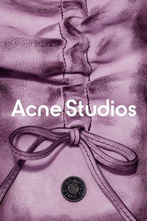 Close-up of a gathered and knotted lilac leather bag with a metal button, featuring the 'Acne Studios' logo in white text.