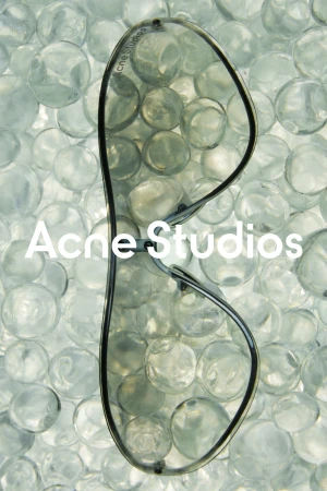 Sunglasses float above a collection of clear glass beads, accented by the 'Acne Studios' logo, which is featured in white text.