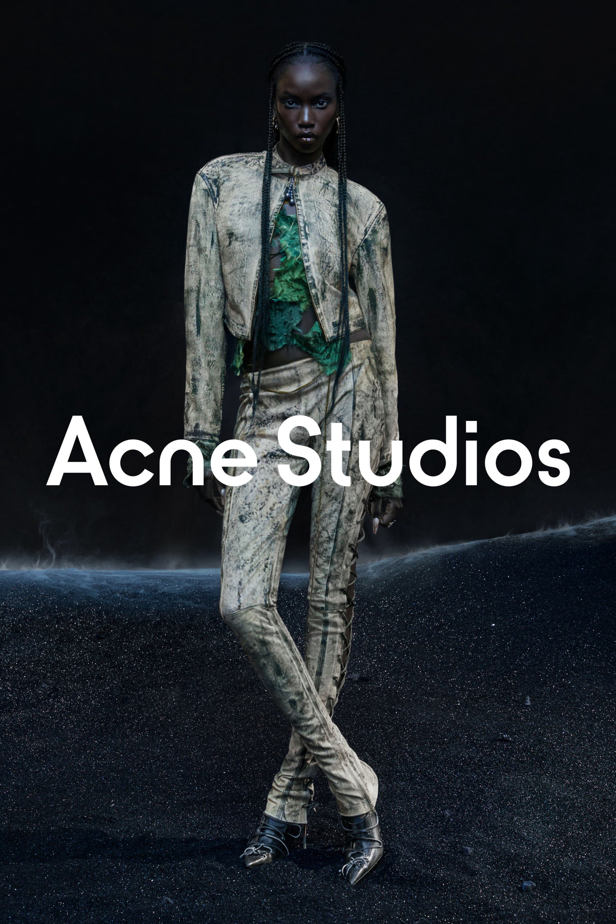 A dark-skinned female model poses in a full-length shot wearing a light beige textured jacket and matching trousers by Acne Studios.
