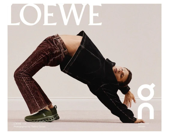 Fashion-forward ad featuring a man in a backbend wearing a dark denim jacket, brown jeans, and green athletic shoes, showcasing the LOEWE and On brands.