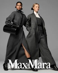 Two female models in grey wool coats and black boots standing against a neutral studio backdrop for Max Mara Fall 2023 campaign.