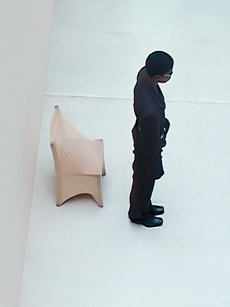 A person standing beside a covered chair on a light-colored surface, captured from a high-angle view.