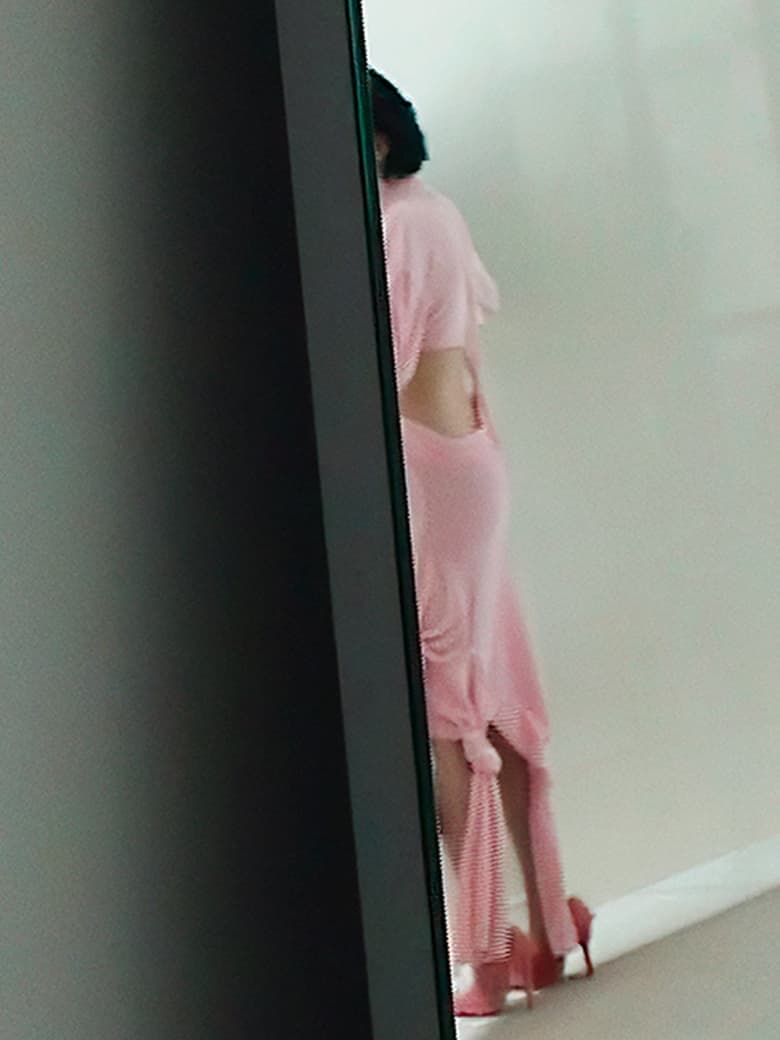 Model in a pink cutout dress and heels standing against a neutral background for Sportmax