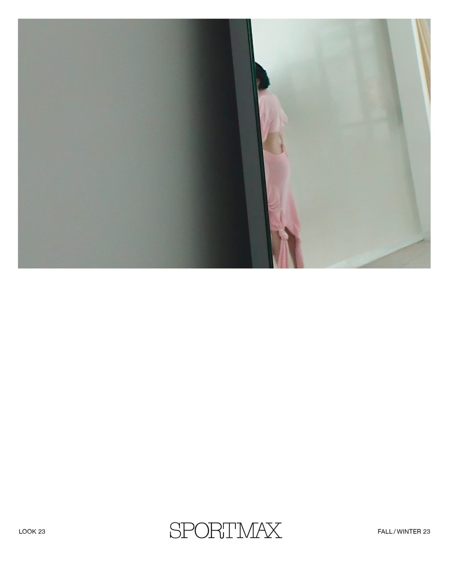 Woman in pink dress and open back stands indoors, viewed through a mirror with a grey frame; SPORTMAX logo at the bottom of the image.