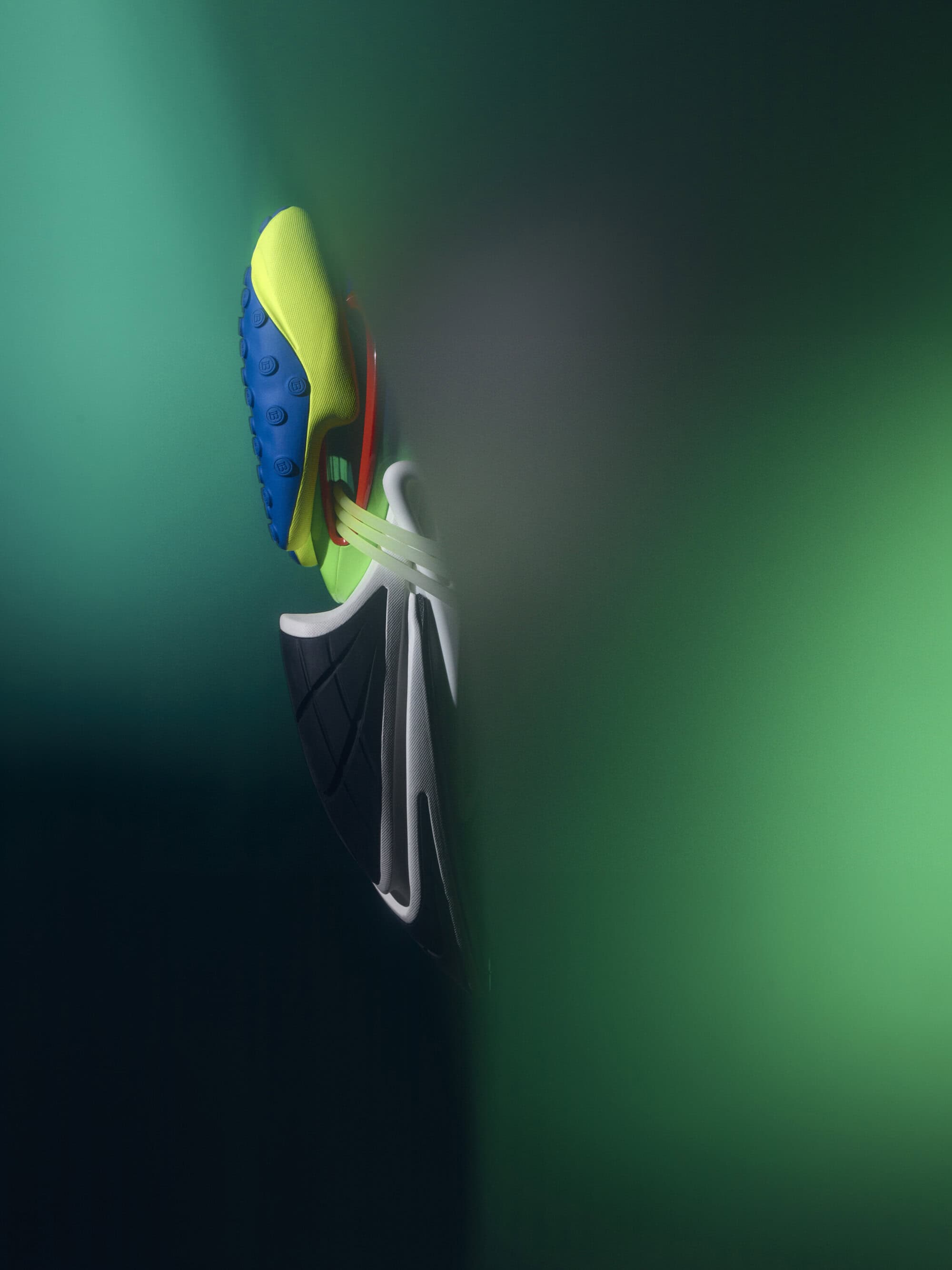 Vibrant running shoe floats against a blurred green background, showcasing its neon yellow, blue, white, and black color scheme.