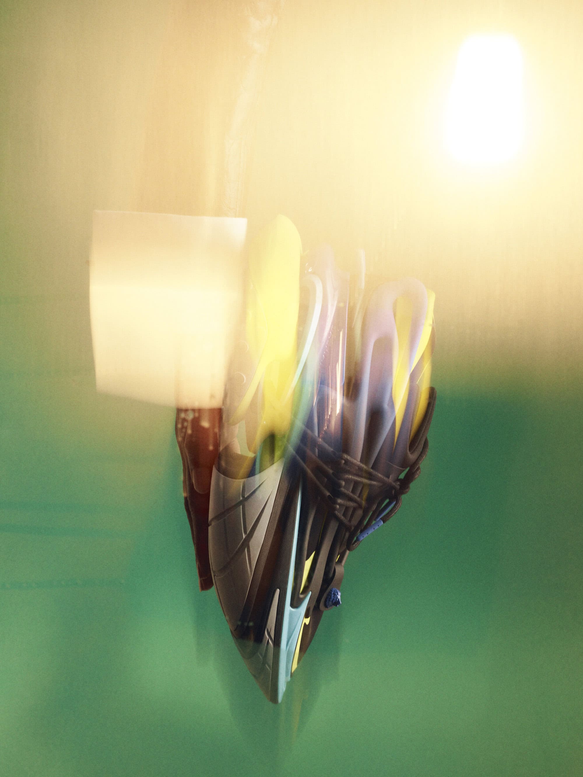Abstract long exposure of a helmet on a green surface featuring blurred shapes, textures, and light, creating an artistic image.