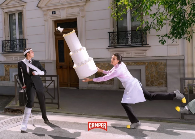 Humorous fashion ad with two people on a street, one injured with a cane and the other appearing to drop a large wedding cake.