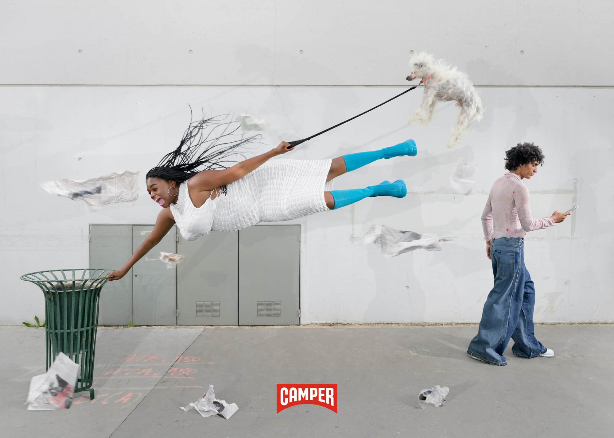 A Black woman in a white dress appears to be floating, holding a dog leash with a white dog and reaching toward a green trash can.