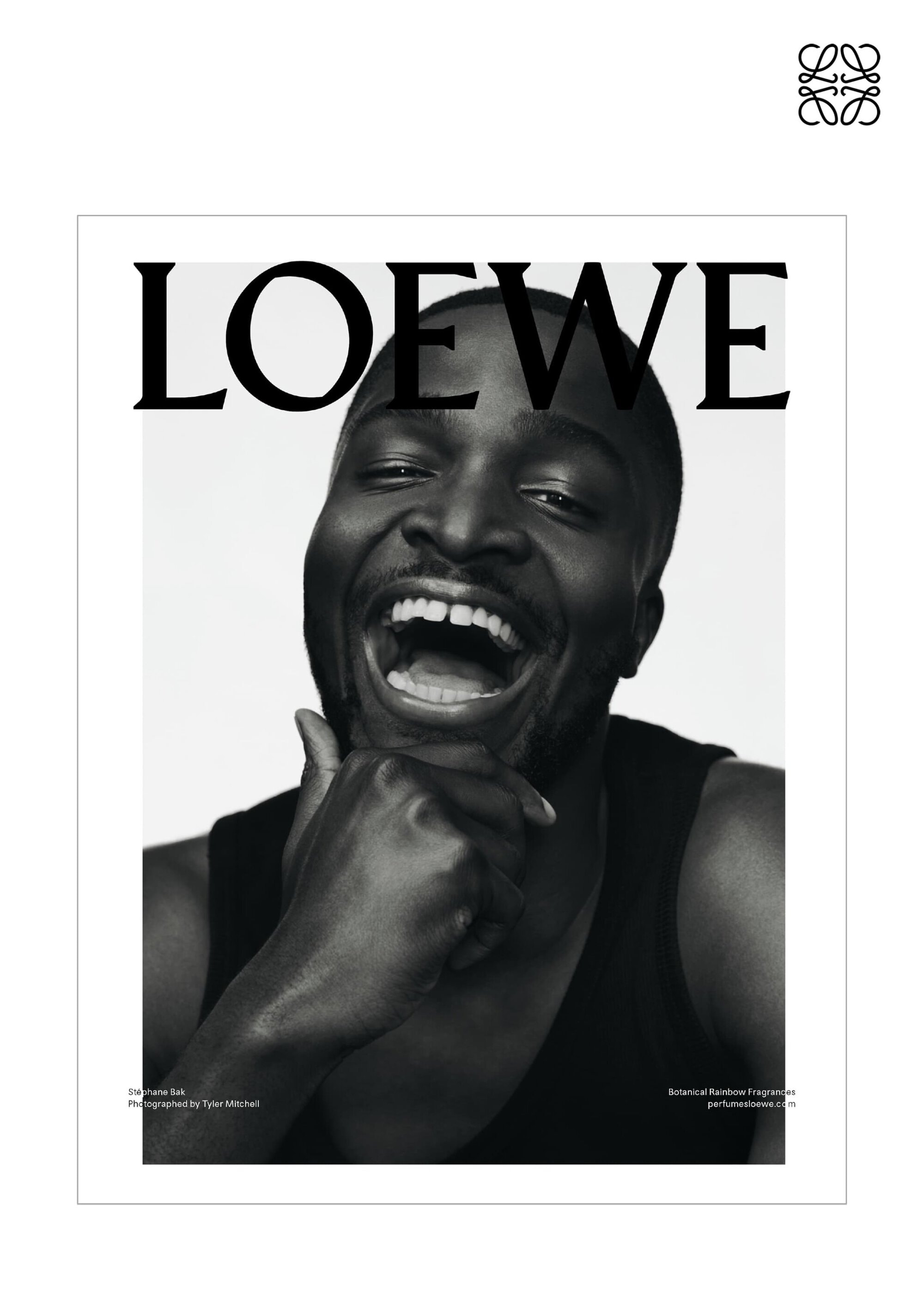 Black and white fashion magazine cover featuring an African American man with his hand to his chin laughing and wearing a tank top.