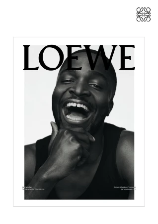 Black and white fashion magazine cover featuring an African American man with his hand to his chin laughing and wearing a tank top.