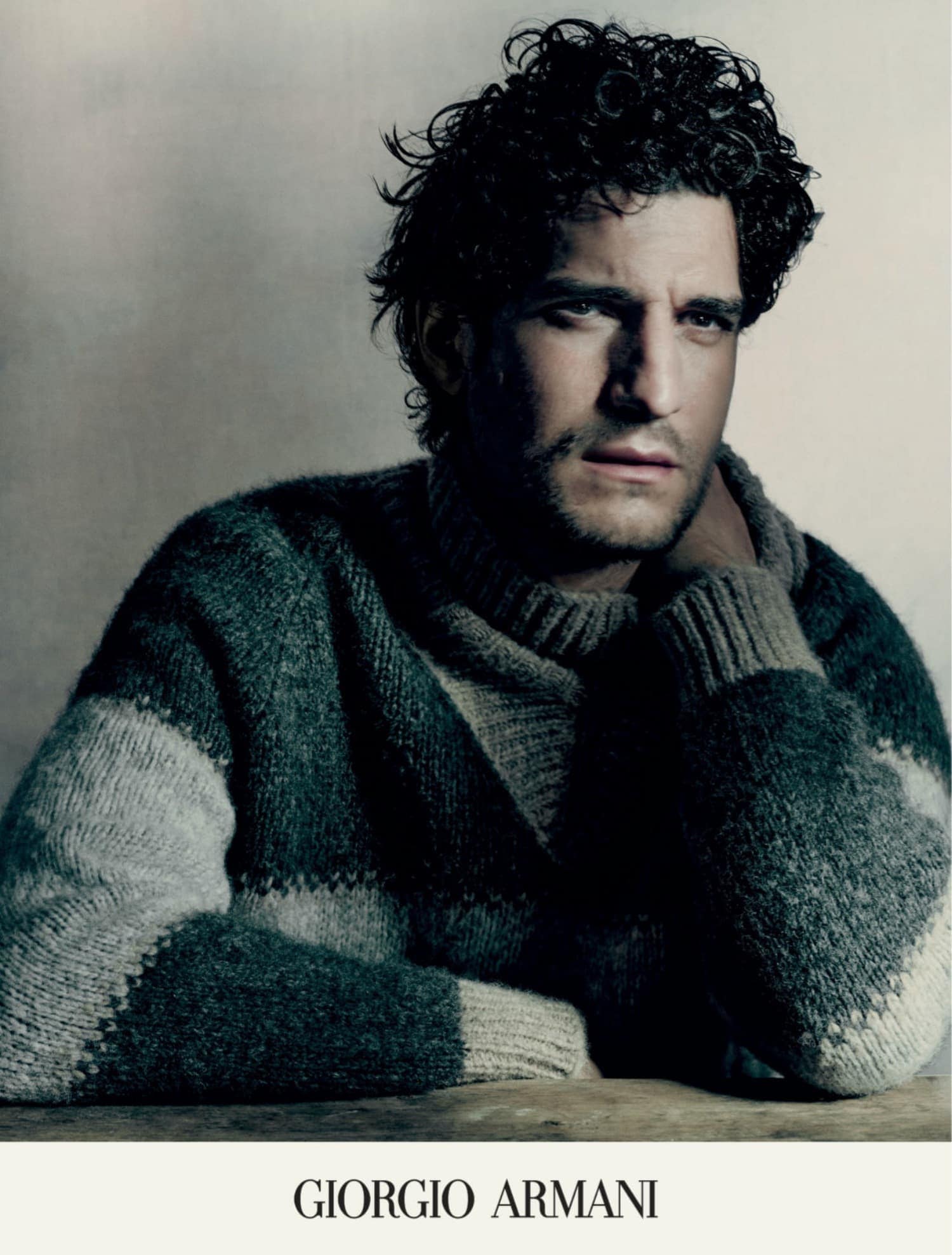 Portrait of a handsome adult male wearing a patterned, heavy knit sweater. Head and shoulders, studio setting, neutral background.