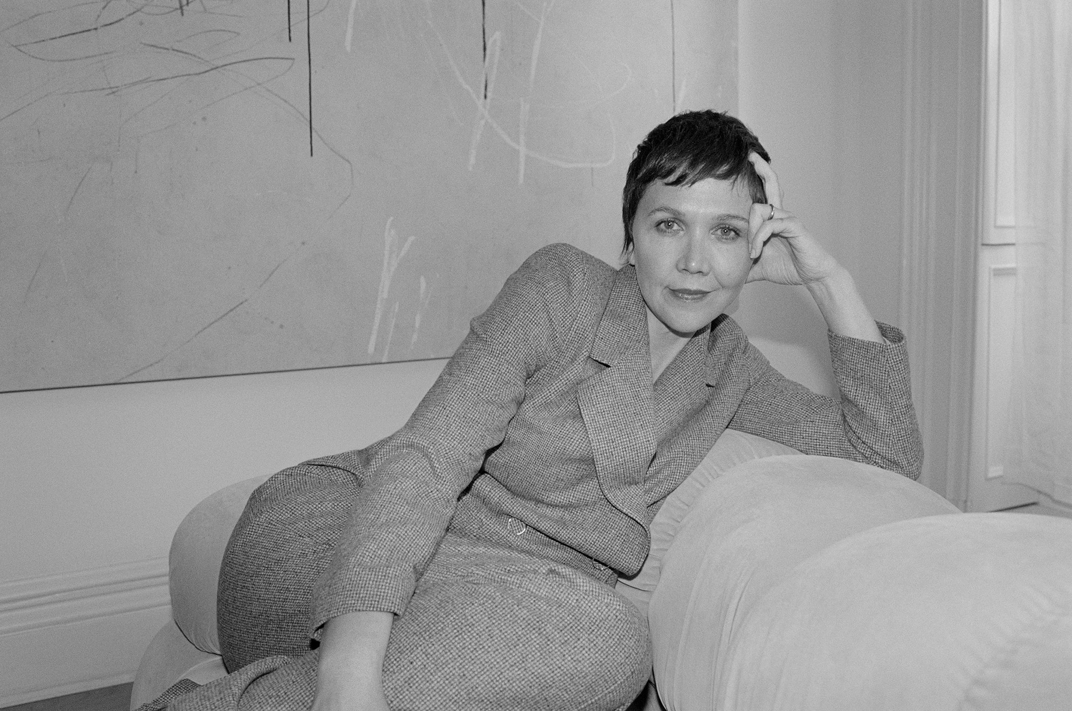 Maggie Gyllenhaal in a grey tweed pantsuit leaning on a sofa for Lafayette 148