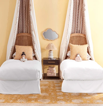 Twin beds with canopies, yellow walls, and neutral-toned carpet create a cozy and inviting kids' room. Decorative cloud mirror.