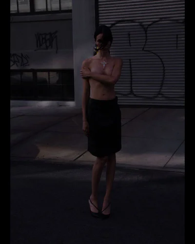 Model standing outdoors on a street wearing a dark skirt and heels against a shuttered wall background
