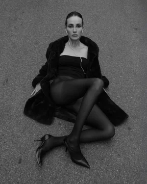 Model seated on asphalt wearing a dark fur coat strapless top and heels for Facilidad Gozo y Gloria test shoot