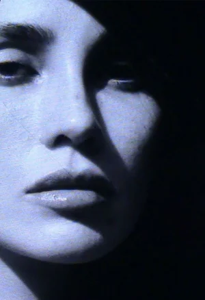 Close-up portrait of a woman with high-contrast dramatic lighting creating deep shadows across her face.