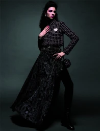 Model Loli-Bahia in a black checkered jacket and patterned skirt for Chanel Fall 2023 ad campaign by Inez and Vinoodh.