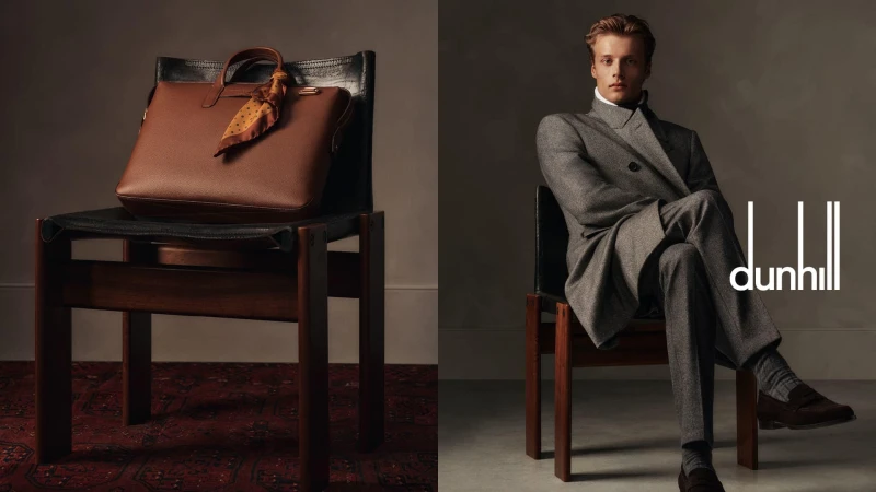Fashion shot features a leather briefcase and a man in a grey suit sitting on chairs against a grey backdrop with logo visible.