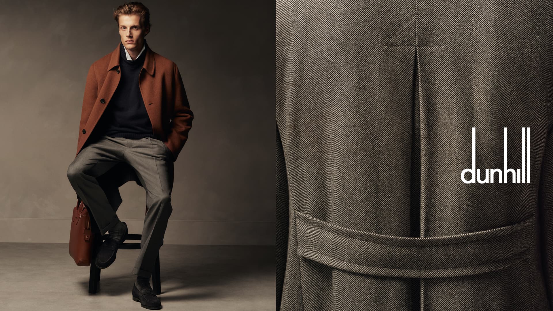 A well-dressed man poses in a brown coat, grey pants, and black shoes holding a leather bag, against a gray backdrop, studio shot.