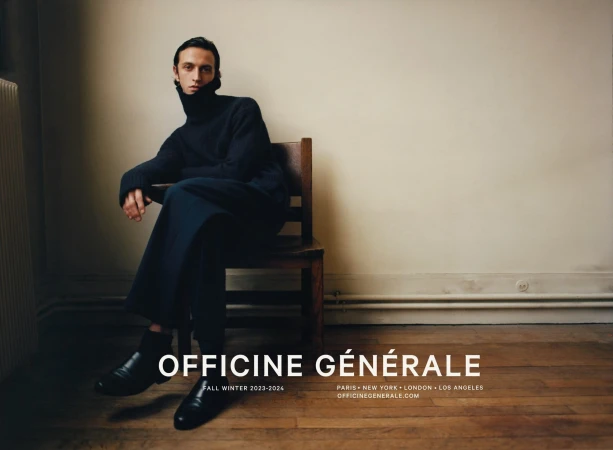 Man wearing dark turtleneck sweater seated on a wooden chair against a plain wall for Officine Generale Fall 2023 campaign.