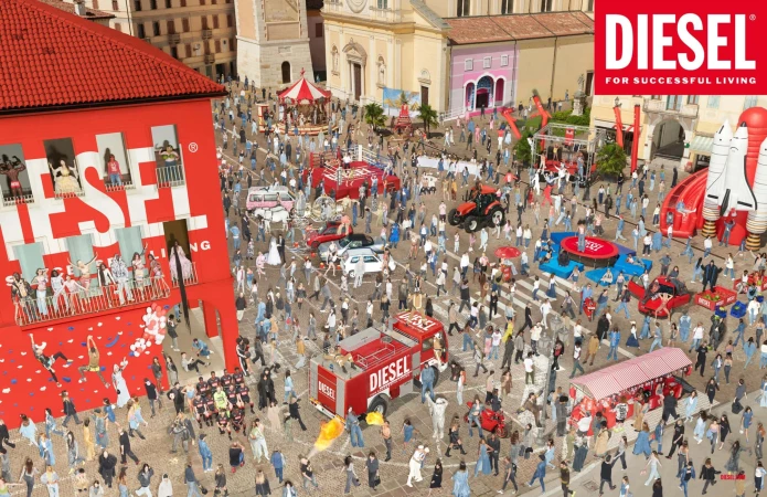 Aerial view of a large crowd of people gathered in a European city square, featuring various vehicles and inflatables under sunny skies.