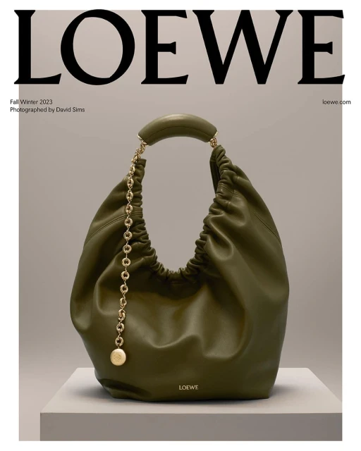 Olive green Loewe hobo bag on a grey platform, featuring a chain detail and set against a grey backdrop with the Loewe logo.
