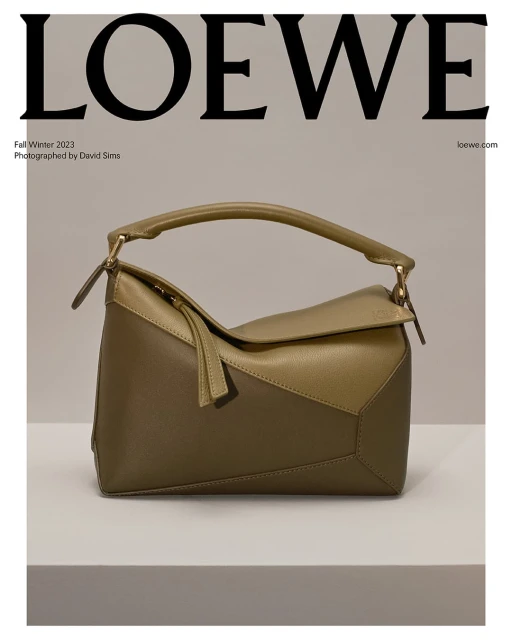 Olive green Loewe Puzzle bag in neutral studio, featuring angular leather panels, top handle, and brand logo in background.